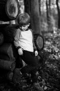 Boy posing against timber in the woods, black and white