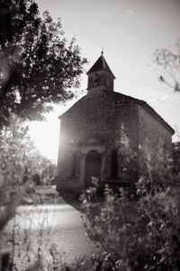 Old church middle of the road with rising sun, sun flard, black and white
