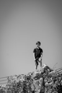 Boy standing tall on rock
