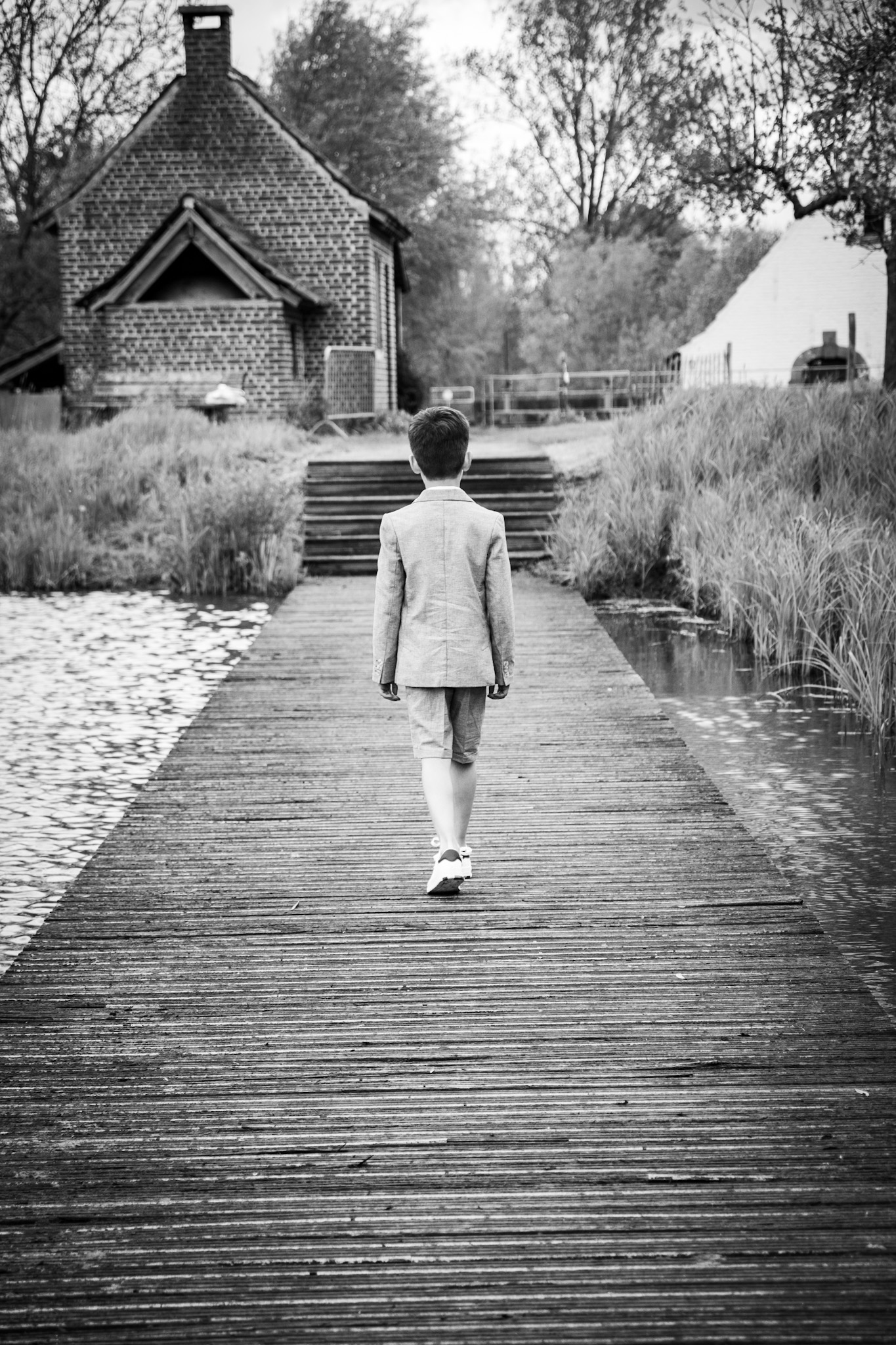 Communie zwart-wit, jonger op houten pad in vijver